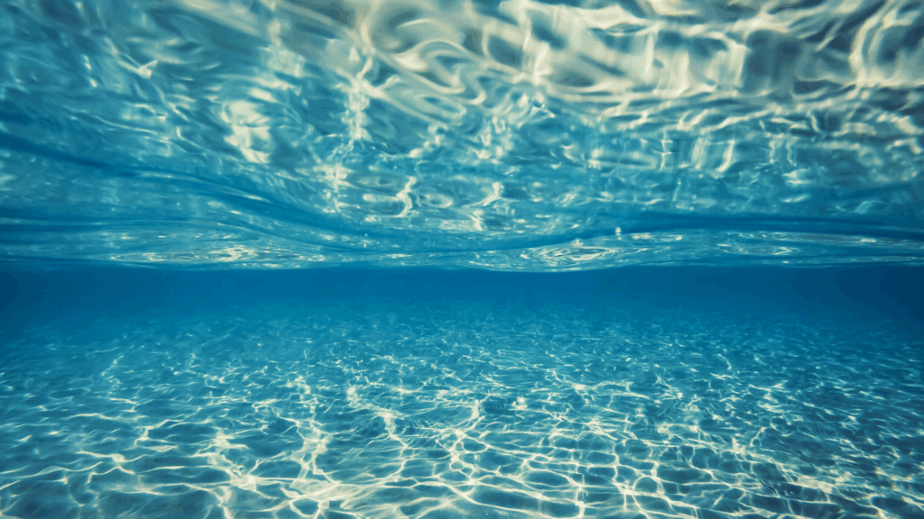 Sunlight shimmering through clear blue water from underwater view