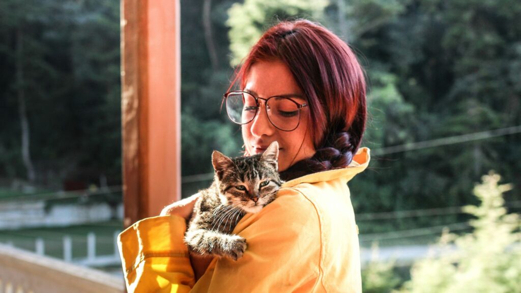 Woman carrying a cat while standing on a porch