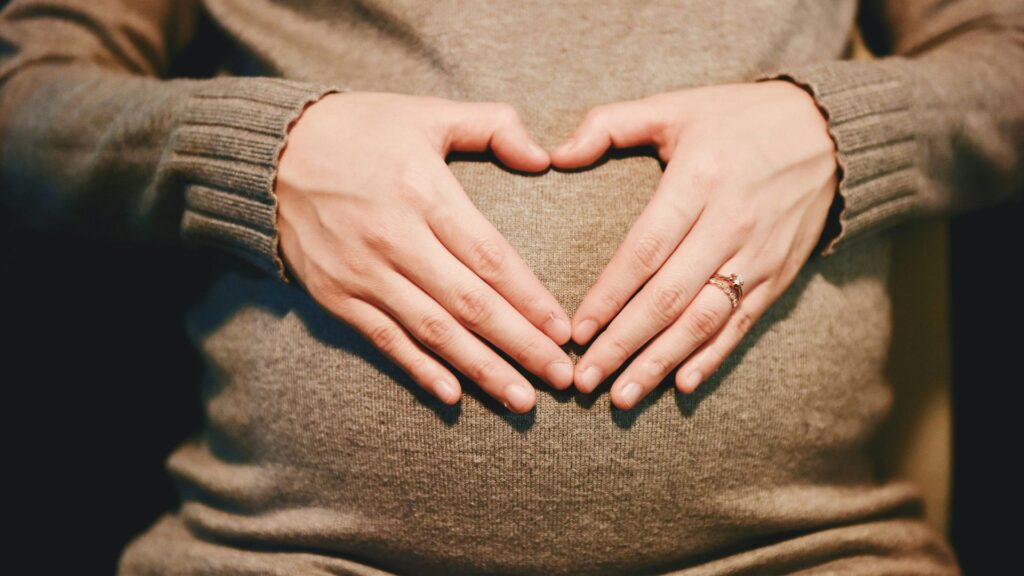 Pregnant woman holding her belly with both hands