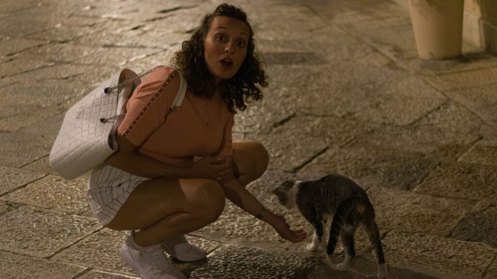 Woman sitting on the floor while holding a cat outdoors