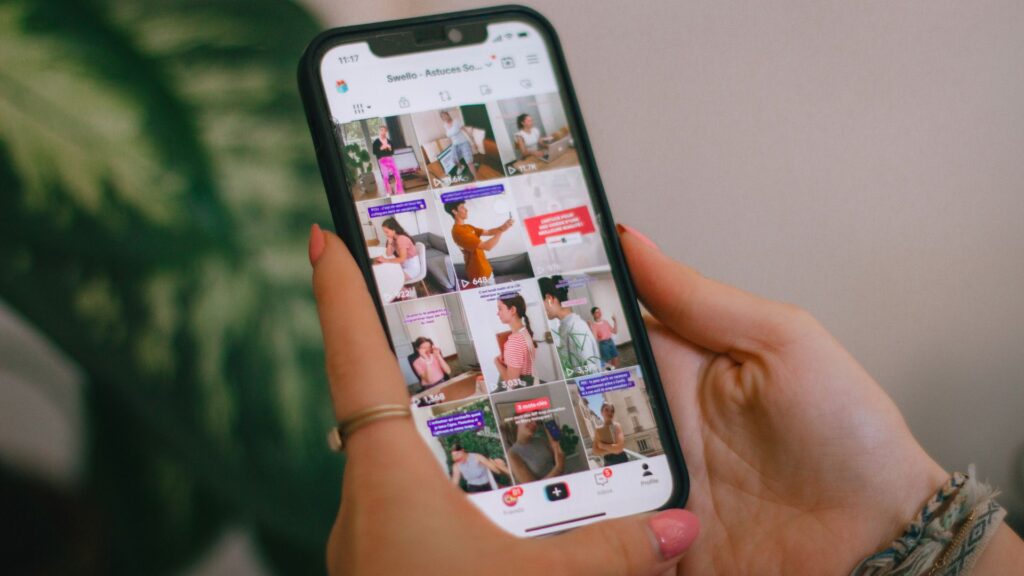 Person holding a smartphone while viewing content on screen