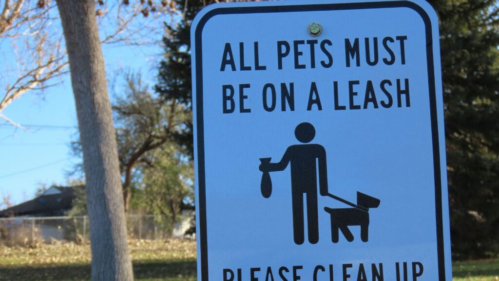 Sign reminding residents to leash pets and clean up dog waste in a shared area