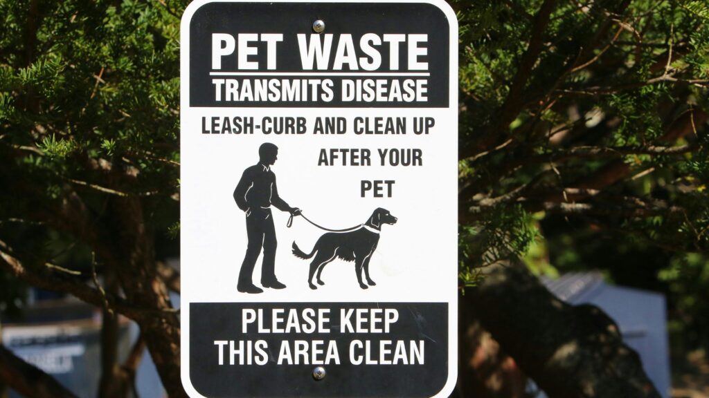 Black and white sign showing a person walking a dog