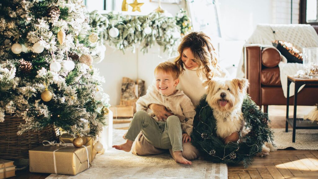 Mother and young son kneeling together while petting their dog outdoors