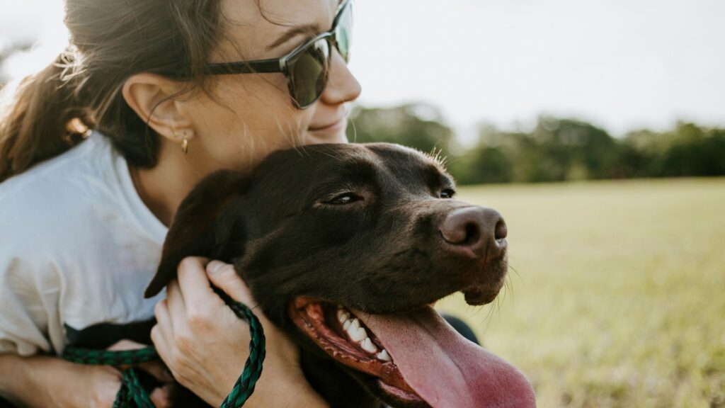 Woman holding and hugging her dog close to her chest indoors