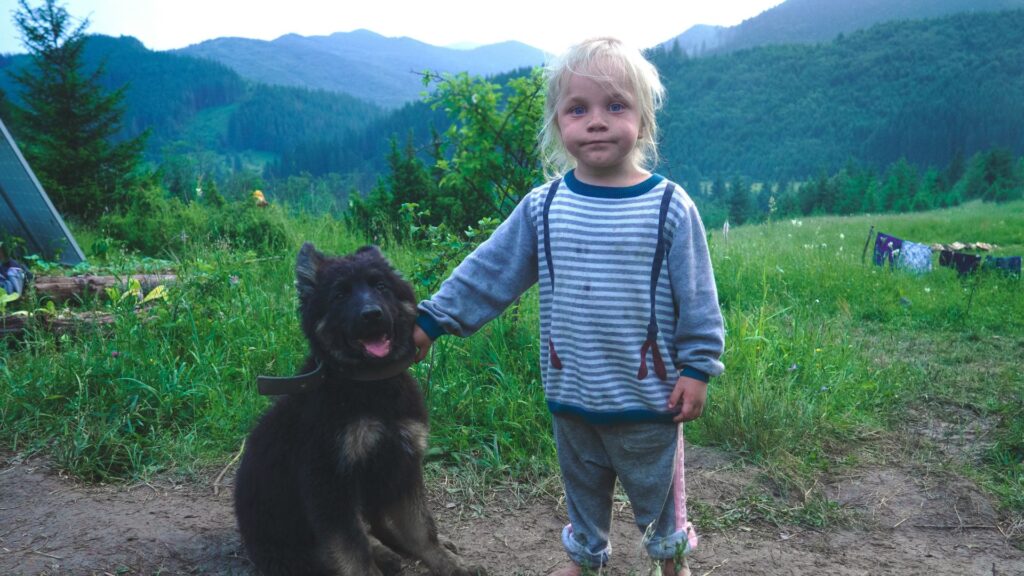 Young woman standing beside a black dog in a casual outdoor setting