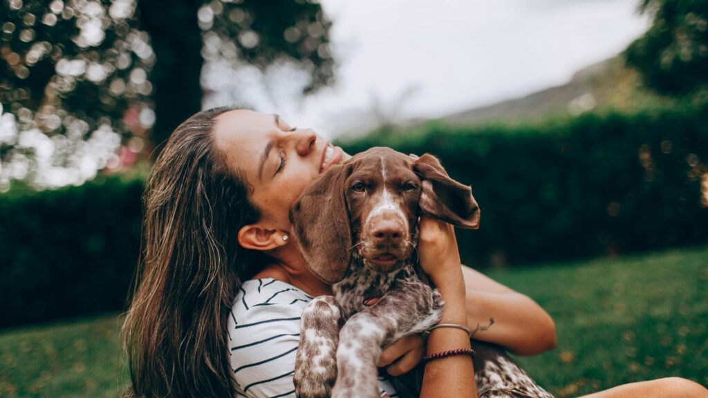 Woman wearing a striped top hugging a brown and white dog