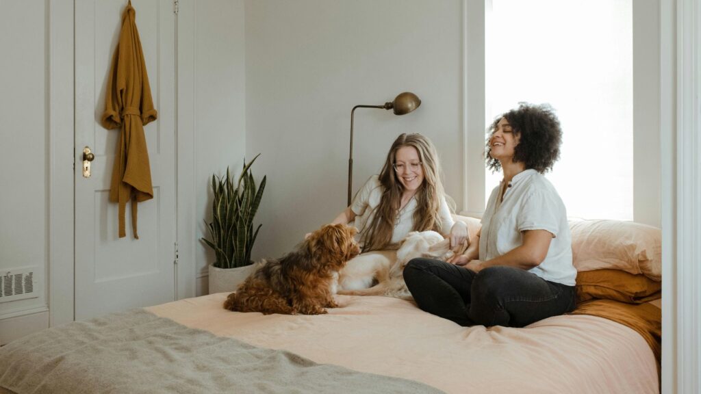 Woman sitting on a bed beside her brown dog in a home setting