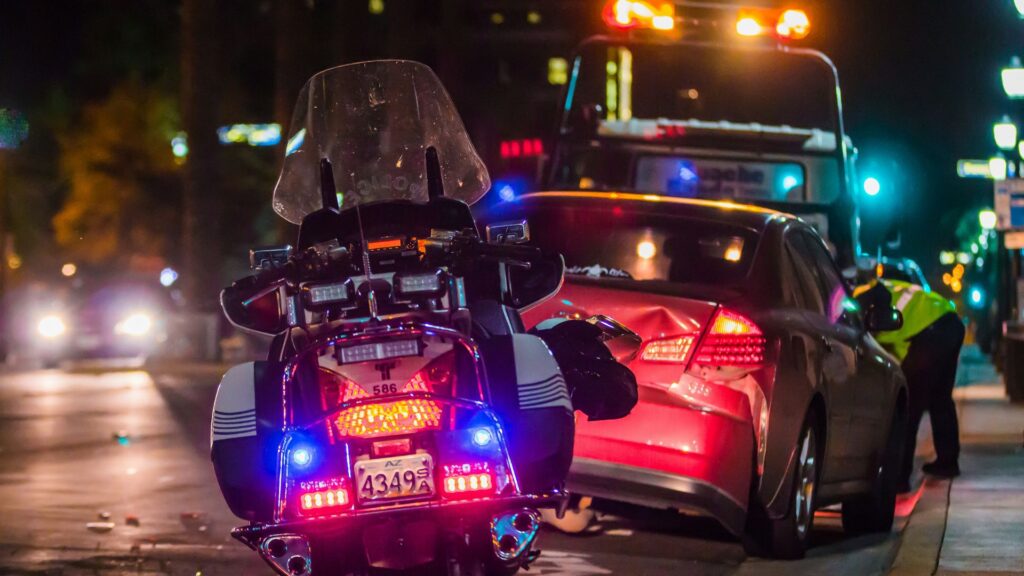 Police officer leaning into a damaged vehicle window after an incident