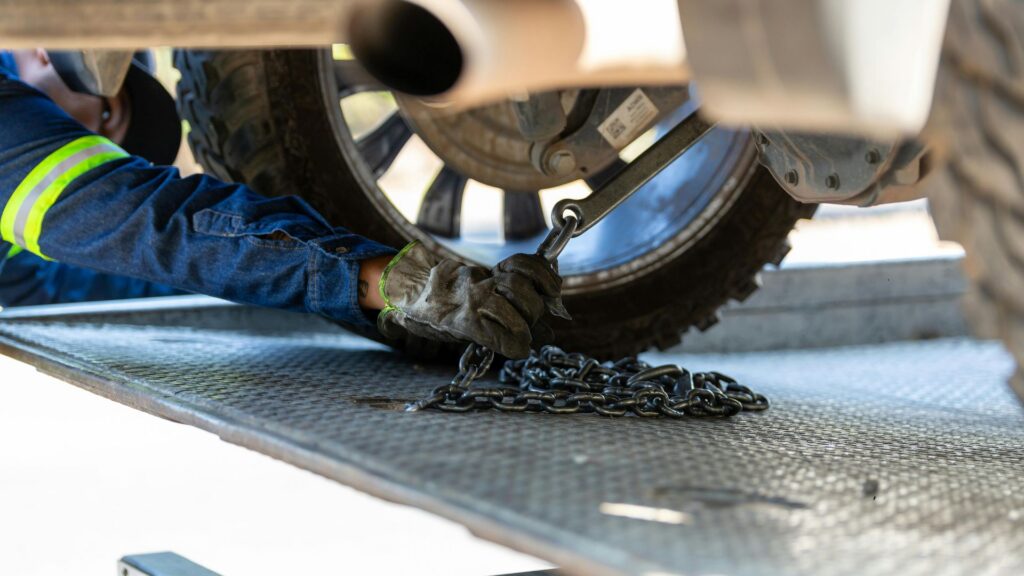 Mechanic arm repairing a vehicle near a tow truck
